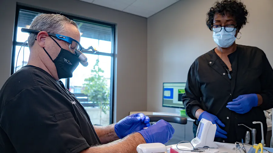 A dental team evaluating a patient's mouth x-ray and before and after pictures of the patient's teeth.