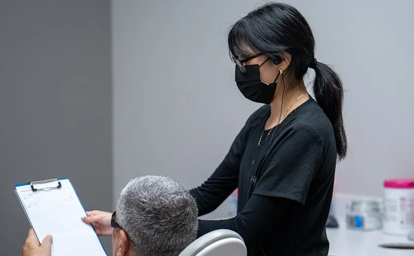 A dental hygienist pointing to a screen in a dental room to a dentist.